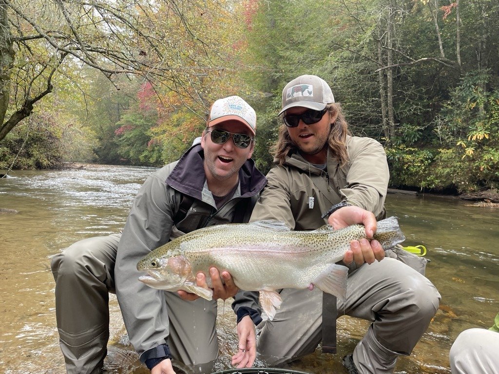 Two anglers holding a rainbow trout on a guided trip